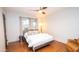 Cozy bedroom with modern ceiling fan, a bright window, wood floors, and an inviting queen-sized bed at 824 W Luke Ave, Phoenix, AZ 85013