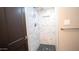 Shower featuring marble tile, a built-in niche, a dark wood door, and pebble flooring at 824 W Luke Ave, Phoenix, AZ 85013