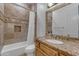 Well-lit bathroom with tiled shower-tub, toilet, and vanity with marble counter and custom wood cabinet at 8320 E Arroyo Hondo Rd, Scottsdale, AZ 85266