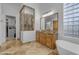 Bathroom featuring a glass shower, soaking tub, granite counters, wood cabinets, and decorative mirrors at 8320 E Arroyo Hondo Rd, Scottsdale, AZ 85266