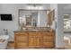 Bathroom featuring granite counters, wood cabinets, stainless steel fixtures, and a large decorative mirror at 8320 E Arroyo Hondo Rd, Scottsdale, AZ 85266