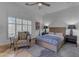 Cozy bedroom featuring a large window, a ceiling fan and chair with throw pillows, and warm lighting at 8320 E Arroyo Hondo Rd, Scottsdale, AZ 85266