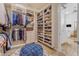 Bright walk-in closet features custom shoe shelves, clothing racks, and a decorative blue ottoman; adjacent to bathroom at 8320 E Arroyo Hondo Rd, Scottsdale, AZ 85266