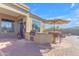 Outdoor kitchen with seating with views of desert landscaping and pool area at 8320 E Arroyo Hondo Rd, Scottsdale, AZ 85266