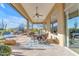 Covered patio includes a dining area, ceiling fans, stone floors, and views of the swimming pool at 8320 E Arroyo Hondo Rd, Scottsdale, AZ 85266