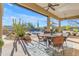 Covered patio with outdoor dining table, chairs, and ceiling fans overlooking desert landscaping at 8320 E Arroyo Hondo Rd, Scottsdale, AZ 85266