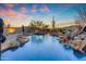 Beautiful pool with rock waterfall feature and lush desert landscaping, perfect for outdoor relaxation at 8320 E Arroyo Hondo Rd, Scottsdale, AZ 85266