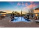 Beautiful pool with rock waterfall, and a desert landscape with mountain views at sunset at 8320 E Arroyo Hondo Rd, Scottsdale, AZ 85266