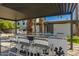 Outdoor kitchen and bar area with granite counters and seating under a modern pergola at 8558 E Indian School Rd # H, Scottsdale, AZ 85251