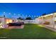 Wide shot of a backyard with manicured lawn, outdoor fireplace, and an outdoor kitchen beneath ambient string lights at 8640 E Dianna Dr, Scottsdale, AZ 85254