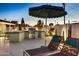 Outdoor kitchen area with barbecue grill and outdoor seating with patio umbrella at twilight at 8640 E Dianna Dr, Scottsdale, AZ 85254