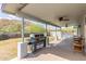 Covered back porch featuring a grill, ceiling fans, and comfortable outdoor seating at 9005 E Grandview Dr, Mesa, AZ 85207