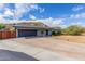 Single-story home featuring a two-car garage, desert landscaping, and privacy fence under a cloudy, blue sky at 9005 E Grandview Dr, Mesa, AZ 85207