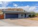 Single-story home featuring a two-car garage, desert landscaping, and privacy fence under a cloudy, blue sky at 9005 E Grandview Dr, Mesa, AZ 85207