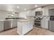 Modern kitchen with stainless steel appliances, white cabinets, an island, and sightlines to the living room at 9005 E Grandview Dr, Mesa, AZ 85207