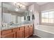 Bathroom featuring double sinks, granite countertop, soaking tub, and neutral color palette at 1250 E Vermont Dr, Gilbert, AZ 85295