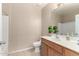 Neutral half bathroom features a wood cabinet, tiled flooring, and a white sink basin with a decorative plant at 14575 W Mountain View Blvd # 11221, Surprise, AZ 85374