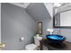 Modern half bath featuring a blue glass bowl sink and decorative wall art at 1531 S Owl Dr, Gilbert, AZ 85296
