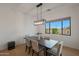 Dining room with a modern light fixture, a wood table with seating for six and a large window at 16832 E Hazeltine Way, Queen Creek, AZ 85142