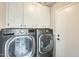 Laundry room with gray washer and dryer and white upper cabinets at 17132 N Silver Path, Surprise, AZ 85374