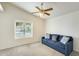 Bright and cozy living room with a comfortable blue sofa, soft carpet, and natural light from a large window at 17132 N Silver Path, Surprise, AZ 85374