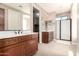 Bathroom with dual sinks, wood cabinets, and a walk-in shower at 18431 W Cinnabar Ave, Waddell, AZ 85355