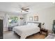 Bright bedroom featuring a white bed, ceiling fan, and a large window overlooking the backyard at 18614 N Conestoga Dr, Sun City, AZ 85373