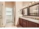 Bathroom featuring double sinks with granite counters, wood cabinets, and a walk-in shower at 19226 N Cave Creek Rd # 109, Phoenix, AZ 85024