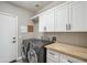 Well-lit laundry room with modern gray washer and dryer, bright white cabinets and butcher block countertop at 19240 N 90Th Pl, Scottsdale, AZ 85255