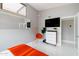 Modern bedroom features an orange color scheme, a large mirror, sleek white dresser with TV, and a light gray painted wall at 2055 W Windsor Ave, Phoenix, AZ 85009