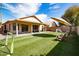 Spacious backyard featuring synthetic grass, a covered patio, and an umbrella for shade at 2323 E Aire Libre Ave, Phoenix, AZ 85022