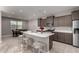 Open kitchen with stainless steel appliances, a large island with stools, and adjacent dining area at 30071 W Indianola Ave, Buckeye, AZ 85396