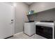Laundry room featuring a modern washer and dryer, tile flooring, and shelving for storage at 30071 W Indianola Ave, Buckeye, AZ 85396