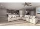 Open-concept living space with L-shaped sofa, ceiling fan, and view of the modern kitchen at 30071 W Indianola Ave, Buckeye, AZ 85396