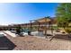 Beautiful backyard with gravel and stone landscaping, a pool, pergolas, and an outdoor dining space at 3202 N 197Th Ave, Buckeye, AZ 85396