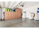 Spacious garage featuring ample cabinet storage, a white refrigerator, and epoxy flooring at 3202 N 197Th Ave, Buckeye, AZ 85396