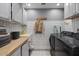 Well-lit laundry room with a utility sink, wooden countertop, white cabinetry, and a modern washer and dryer at 3834 E Shaw Butte Dr, Phoenix, AZ 85028