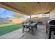 Covered outdoor patio area featuring a rustic wooden dining table with seating and a built-in BBQ grill at 3834 E Shaw Butte Dr, Phoenix, AZ 85028