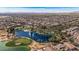 Picturesque aerial view of a Primary-planned community with a golf course, lake with fountains, and lush landscaping at 42660 W Oakland Dr, Maricopa, AZ 85138