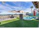 Landscaped backyard with a beautiful pool, turf lawn, firepit and custom painted wall at 42660 W Oakland Dr, Maricopa, AZ 85138
