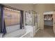 This spacious bathroom has a soaking tub, a glass-enclosed shower, and a privacy window with light-filtering blinds at 42660 W Oakland Dr, Maricopa, AZ 85138