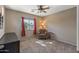 Cozy bedroom with a ceiling fan, neutral carpet, and a comfortable reading chair by the window at 42660 W Oakland Dr, Maricopa, AZ 85138