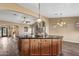 Kitchen island with a bar and wooden cabinets offers ample counter space and views into the living room at 42660 W Oakland Dr, Maricopa, AZ 85138