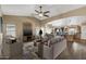 Open-concept living room with wood floors, ceiling fan, and seamless flow to kitchen and dining areas at 42660 W Oakland Dr, Maricopa, AZ 85138