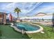 Resort-style backyard featuring a sparkling pool, desert mural, putting green, and lush turf at 42660 W Oakland Dr, Maricopa, AZ 85138