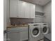 Well-equipped laundry room with modern washer and dryer, complemented by cabinets and sink at 4878 W Elijah Ln, San Tan Valley, AZ 85144