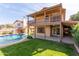 A backyard view showcasing a two-story house with a balcony overlooking a refreshing swimming pool and green grass at 4946 W Evans Dr, Glendale, AZ 85306