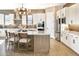 Bright kitchen featuring white cabinets, a marble-top island with seating, stainless steel appliances, and decorative lighting at 5719 S Quartz St, Gilbert, AZ 85298