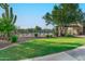 Community pool area features a black metal fence, mature desert plants, grassy area, and ramada at 6965 E Hacienda La Noria Ln, Gold Canyon, AZ 85118