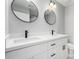 Modern bathroom with dual sinks, white cabinets, black hardware, and large round mirrors at 700 N D St, Eloy, AZ 85131